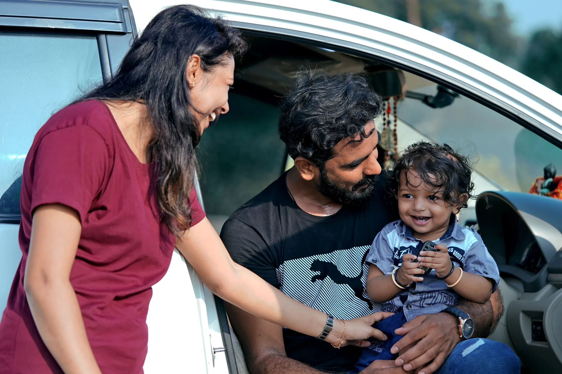 Indian family together beside a car